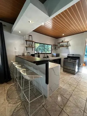 a kitchen with a counter and stools in it at Casa Bahia Heliconia in Uvita