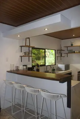 a kitchen with three bar stools and a counter at Casa Bahia Heliconia in Uvita