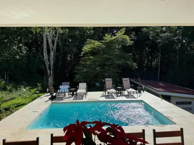 a swimming pool with chaises and chairs in a backyard at Casa Rio Tortuga - Butterfly in Ojochal