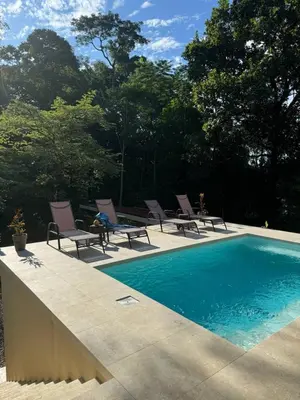a swimming pool with lounge chairs next to at Casa Rio Tortuga - Butterfly in Ojochal