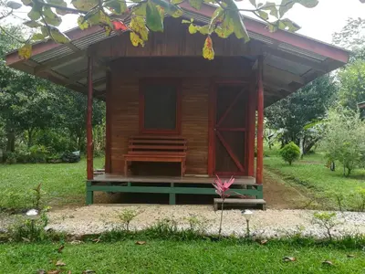 a wooden cabin with a bench in the grass at Rincon Verde in Bijagua