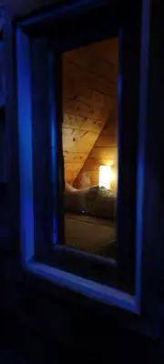 a mirror reflecting a room with a bed and a lamp at Cabañas La Madriguera