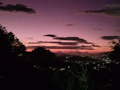 a purple and pink sky with trees and a city at Cabañas La Madriguera