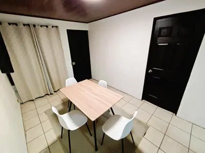 a room with a table and white chairs and a black door at Apartment JESALU, just 3 minutes from the Airport in San Antonio