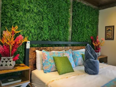 a bedroom with a green wall and a bed with pillows at Villa Tucan in Agua Azul