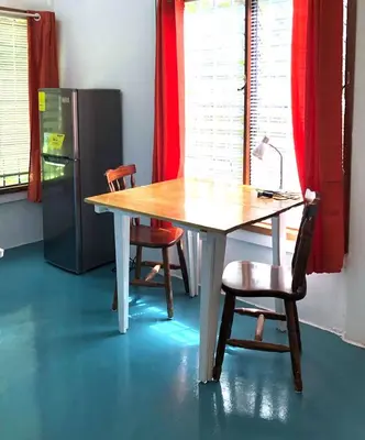 a wooden table with two chairs and a refrigerator at Ojochal, Costa Rica artist owned property in Ciudad Cortés