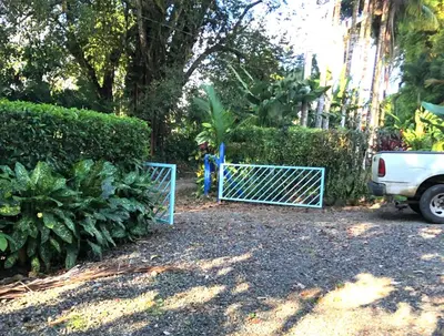 a blue gate in a yard next to some bushes at Ojochal, Costa Rica artist owned property in Ciudad Cortés