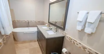 a bathroom with a tub and a sink and a mirror at 2 Bedroom Condo in Croc's Casino Resort in Jacó