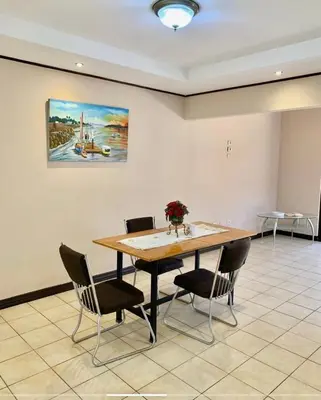 a dining room table with chairs and a painting on the wall at Casa cerca Aeropuerto in Tapantí