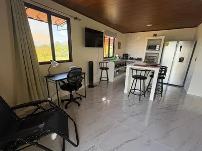 a kitchen and living room with a table and chairs at Cabin Casove in El Castillo de La Fortuna