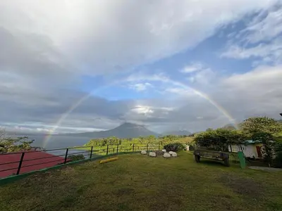 a rainbow in the sky over a yard with a field at Cabin Casove in El Castillo de La Fortuna