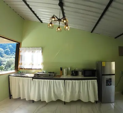a kitchen with a table with a white table cloth at Cabaña Brisas Del Río in Parrita