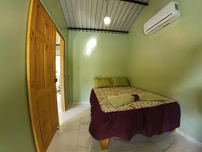 a bedroom with a bed in a green room at Cabaña Brisas Del Río in Parrita