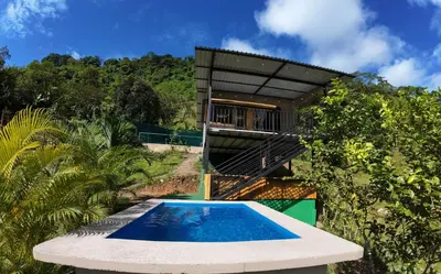 a swimming pool in front of a house at Cabaña Brisas Del Río in Parrita