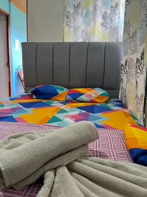 a bed with a colorful comforter on top of it at GuestHouse Detours CR in Fortuna