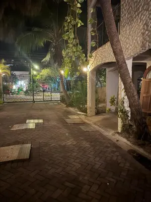 a courtyard at night with a fence and palm trees at Tama Magico in Tamarindo