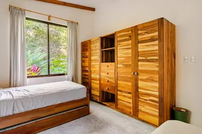 a bedroom with a bed and a large window at Pelada Jungle Nest 5-Min Walk to Beach & River in Nosara
