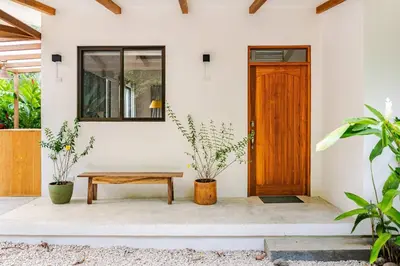 a front door of a house with a bench and plants at Pelada Jungle Nest 5-Min Walk to Beach & River in Nosara