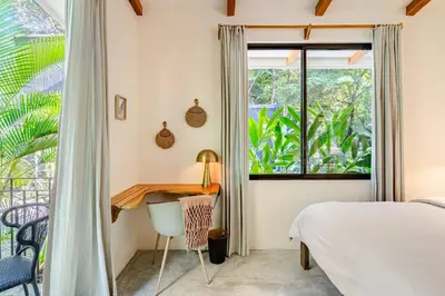 a bedroom with a bed and a desk and a window at Pelada Jungle Nest 5-Min Walk to Beach & River in Nosara