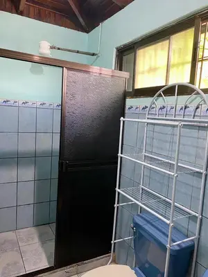 a bathroom with a toilet and a door with shelves at Casa Marisol in Quepos