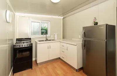 a kitchen with a stainless steel refrigerator and white cabinets at Tiny Homes Tamarindo in Tamarindo