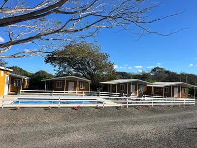 a row of lodges with a pool and a fence at Tiny Homes Tamarindo in Tamarindo