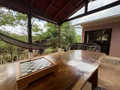 a room with a wooden table and a hammock at Pura Noche Guanacaste in Marbella