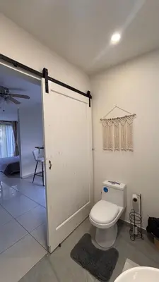 a bathroom with a white toilet and a door at Miles Away Boutique Villa in Cóbano