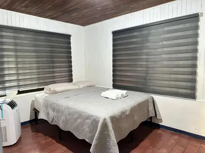 a bed in a room with two large windows at Beach house Punta Morales in Morales
