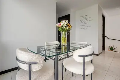 a glass table with chairs and a vase of flowers at Vistas del Sol-Apartamento Entero in Pedregoso