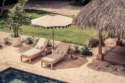 two chairs and an umbrella next to a swimming pool at Casa Tanamera 5BR Private Retreat in Hacienda Pinilla in Tamarindo