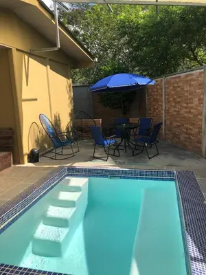 a pool with chairs and a table and an umbrella at Macaws Villa in Tapantí