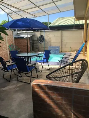 a patio with a table and chairs and an umbrella at Macaws Villa in Tapantí