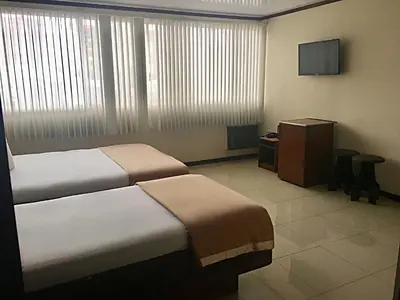 a hotel room with two beds and a television at Hotel Ambassador in San José