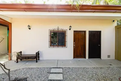 a bench sitting in front of a white house at PuraVida lifestyle at Casa Caoba in Playa Flamingo