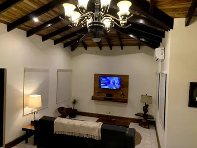 a living room with a couch and a tv on the wall at PuraVida lifestyle at Casa Caoba in Playa Flamingo