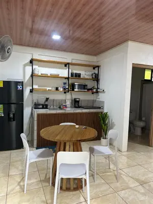 a kitchen with a wooden table and white chairs at El refugio in Nosara