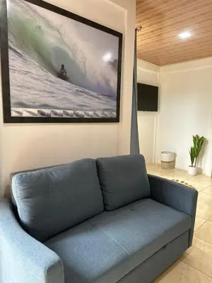 a couch in a living room with a painting on the wall at El refugio in Nosara