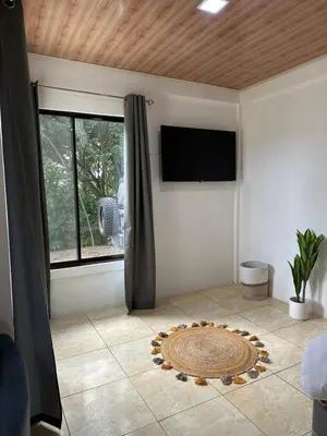 a living room with a flat screen tv and a rug at El refugio in Nosara