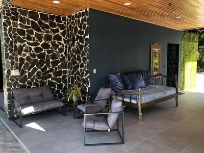 a patio with a couch and chairs and a stone wall at Club Fred Aparthotel in Punta Mala