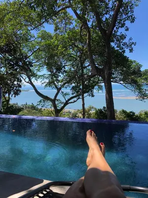 a person laying on a chair next to a swimming pool at Club Fred Aparthotel in Punta Mala