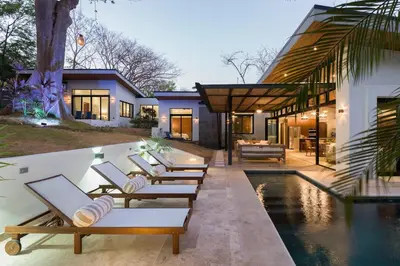a row of lounge chairs in front of a house at Luxury 3BR Gated Villa - Private Pool in Tamarindo in Tamarindo