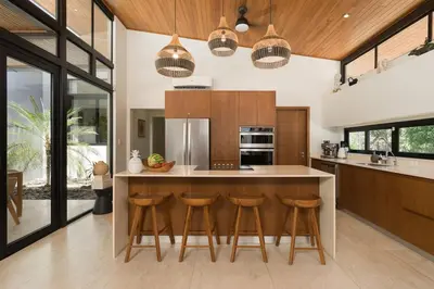 a kitchen with wooden cabinets and a island with bar stools at Luxury 3BR Gated Villa - Private Pool in Tamarindo in Tamarindo