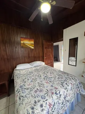 a bedroom with a bed with a floral bedspread at Casa Aurora, Nuevo Arenal in Arenal