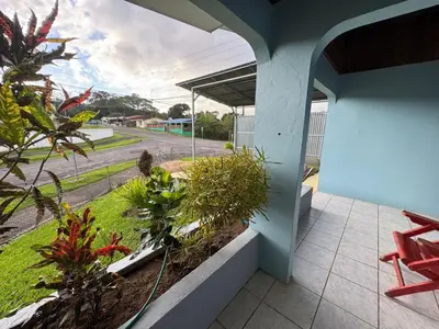 a porch with a red chair and a view of a street at Casa Aurora, Nuevo Arenal in Arenal