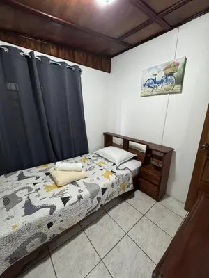 a bedroom with a bed in a room with black curtains at Casa Aurora, Nuevo Arenal in Arenal