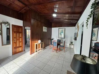 a living room with a table and a wooden ceiling at Casa Aurora, Nuevo Arenal in Arenal