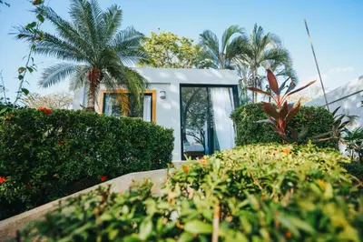 a small white house with trees and plants at Hotel Bohemian Lagarto in Santa Cruz