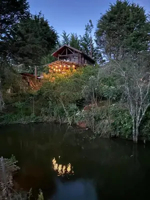 a house sitting on top of a hill next to a lake at Cabaña de Montaña El Jardin in Jardín