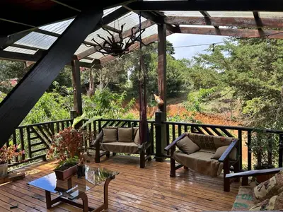 a wooden deck with two chairs and a table at Cabaña de Montaña El Jardin in Jardín
